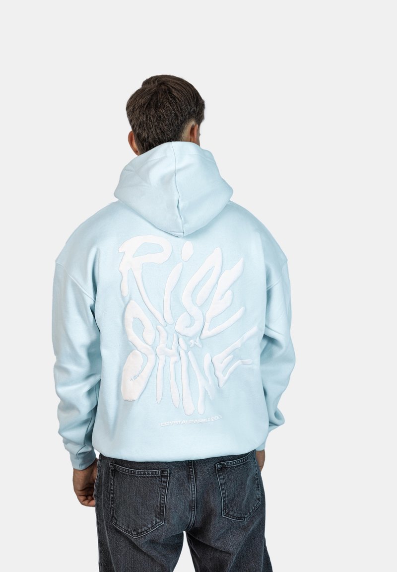 Felpa leggera di colore azzurro con vestibilità oversize, caratterizzata dalla scritta bianca "RISE & SHINE" sul retro. Tessuto testurizzato e cappuccio regolabile.