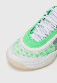 Scarpa sportiva con parte superiore in mesh verde e accenti bianchi, suola in gomma liscia e dettagli riflettenti grigi. Lacci bianchi, collo imbottito.