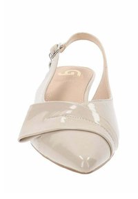 Sandały typu slingback w błyszczącej beżowej skórze lakierowanej. Posiadają spiczasty nos i krzyżowy pasek. Regulowane zapięcie na kostkę.