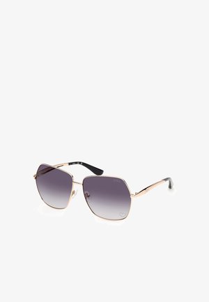 Gafas de sol con montura metálica dorada, lentes grandes cuadradas con degradado oscuro y patillas negras, mostradas sobre fondo blanco.