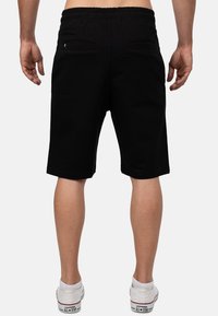 Zwarte sportieve shorts van zachte stof, met een comfortabele elastische tailleband en twee achterzakken voor opslag. Standaard pasvorm, omgezoomd.