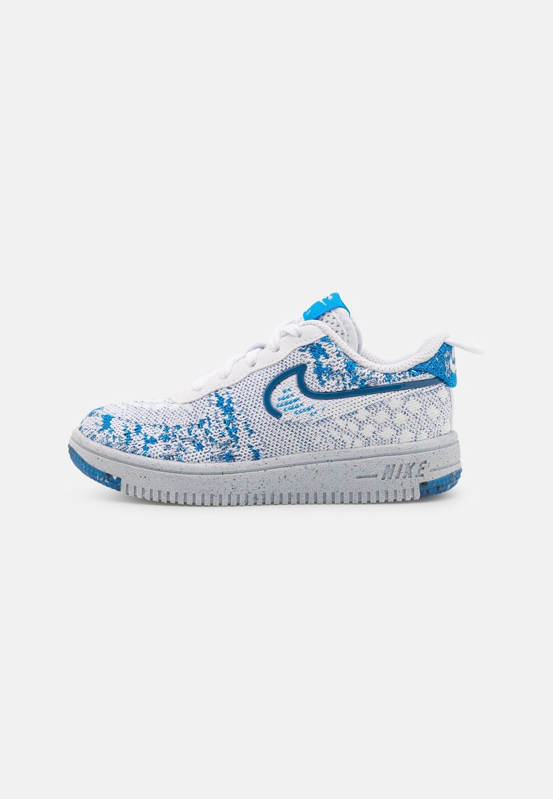 Baskets en maille Nike blanches et bleues avec une semelle grise tachetée et un logo swoosh bleu sur le côté, vues de profil extérieur.