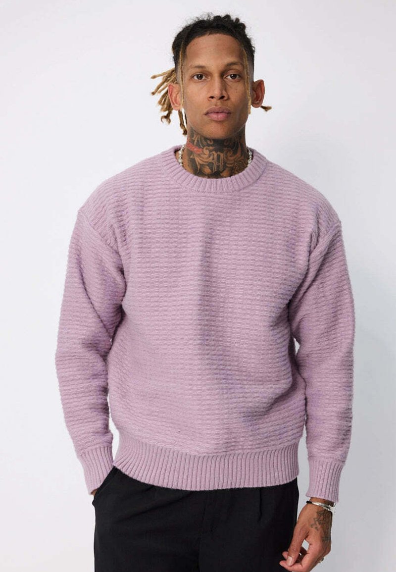 Sweatshirt texturé violet clair à col rond, avec des poignets et un ourlet côtelés. Porté avec un pantalon noir à coupe décontractée.