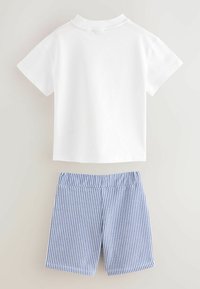 T-shirt bianco in cotone con maniche corte abbinato a pantaloni corti a righe blu e bianche con vita seamless e bordi rifiniti.