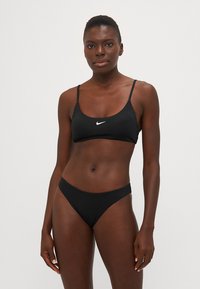 Ensemble de bikini noir en tissu doux ; présente un design simple avec des bretelles ajustables et un logo minimaliste sur le haut.