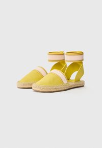 Espadrillas di stoffa gialle con suola in juta intrecciata, dotate di cinturini alla caviglia a righe rosa e gialle e design con ritagli.