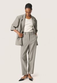 Gråternet blazer med en afslappet pasform, parret med matchende tapered bukser og en hvid ribbet top. Sorte slingback-sko fuldender looket.