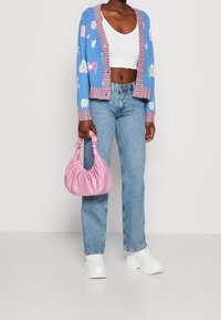 Blå strikket cardigan med farverige mønstre, pink stribede kanter, hvid top, lyseblå jeans og en pink læderhåndtaske med en afslappet design.