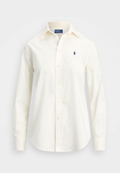 Valge pikade varrukatega puuvillane särk, millel on nööpidega krae, vasakul rinnal on väike sinine logo ning tavalised mansetid.