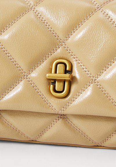 Quilted beige leather handbag featuring a glossy finish, gold hardware, and a prominent clasp detail at the center.
