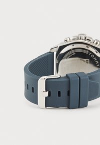 Correa de reloj de silicona azul con un cierre de metal, que presenta una superficie texturizada y múltiples agujeros de ajuste para la variación del tamaño.