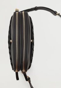 Sort håndtaske med en struktureret overflade, dobbelt guld lynlås og en aftagelig rem. Har et kompakt design og glatte læderdetaljer.