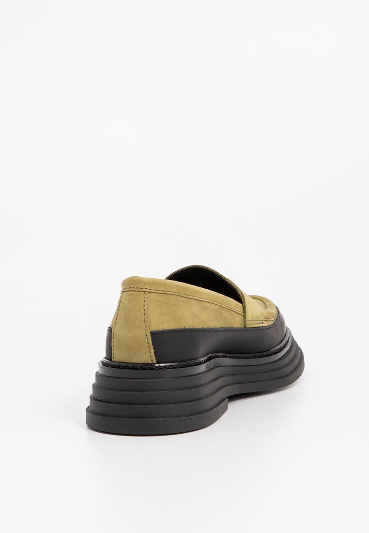 Zielone zamszowe buty wsuwane na czarnych gumowych podeszwach, z warstwowym wzornictwem i gładką fakturą. Brak widocznych elementów metalowych lub wzorów.