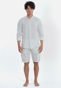 Witte linnen shirt met een bandkraag en knopen, gecombineerd met bijpassende cargoshorts. Beide kledingstukken hebben een lichte, ademende textuur.