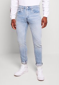 Lichtblauwe denim jeans met een slanke pasvorm, voorzien van een klassieke vijf-pocket design, opgerolde mouwen en subtiele vervaging. Draag ze met witte sneakers.