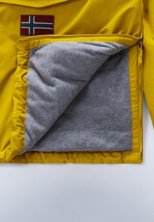 L'intérieur de la veste jaune présente un doux doublage en polaire grise et une poche zippée. Un patch de drapeau norvégien est cousu à l'extérieur.