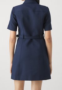Abito Navy a maniche corte con vita svasata, design strutturato e tessuto morbido. Presenta un colletto e una vestibilità su misura.
