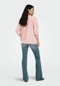 Lys pink skjorte med puffede ærmer, samlede manchetter og en løs pasform, parret med lys blå flagrende jeans. Glat stof og afslappet design.