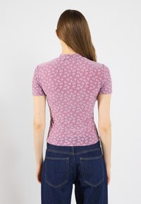 Kurzarmpullover in Pink mit einem strukturierten Muster aus kleinen Bären-Silhouetten. Der Stoff hat eine weiche, durchsichtige Qualität und ein figurbetontes Design.