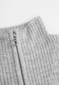 Szary, prążkowany kołnierz swetra z dzianiny z srebrnym, okrągłym suwakiem, podkreślający fakturę materiału i wyrafinowaną konstrukcję.