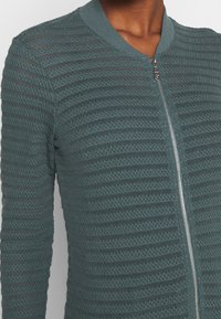 Groene gebreide bomberjack met horizontale strepen, een geribde kraag en een ritssluiting aan de voorkant. Lichtgewicht en met een textuurrijk design.