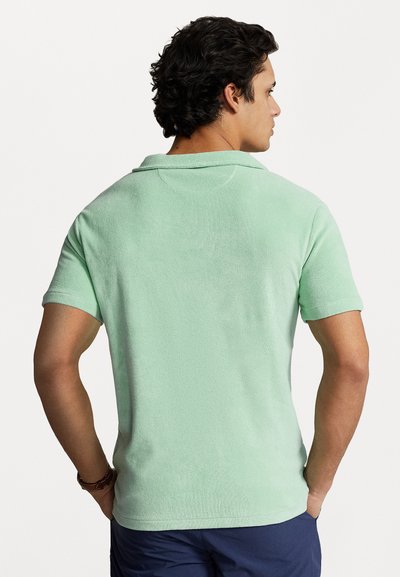 Groen poloshirt met korte mouwen, gemaakt van een gestructureerde stof, met een zachte kraag en een gladde afwerking. De achterkant toont subtiele stikdetails.
