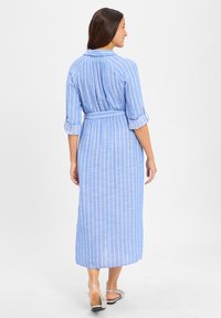 Blue striped dress with a belted waist, collar, and three-quarter sleeves. Lightweight fabric with a flowing shape, reaching mid-calf.
