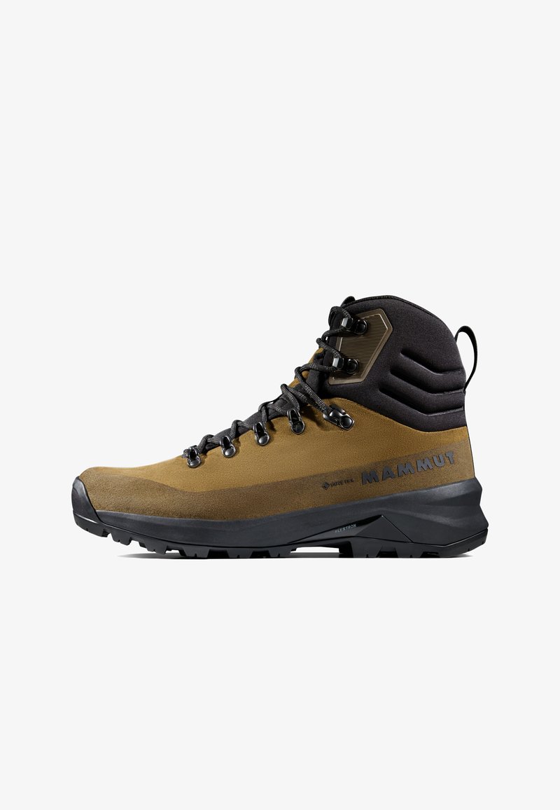 Bruine en zwarte hoge wandelschoen met vetersluiting, gevoerde enkelsteun, robuuste zool en "Mammut"-logo aan de zijkant.