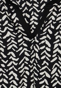 Tessuto nero con un motivo astratto bianco di forme irregolari, con un design a V e un bordo nero a contrasto lungo il colletto.