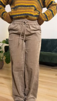 Μπεζ παντελόνι από κορντόρι με άνετη εφαρμογή, διαθέτει ελαστική μέση, κορδόνι ρύθμισης και διακριτική κάθετη ριγωτή υφή.