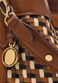 Brązowa skórzana torebka charakteryzująca się plecionym wzorem w odcieniach brązu, czerni i kremu. Zawiera złote akcenty i dekoracyjną zakładkę.