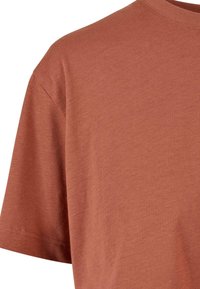 Košile z bavlny v rezavé barvě s kulatým výstřihem a krátkými rukávy; má hladkou texturu a jemné švy na lemu.