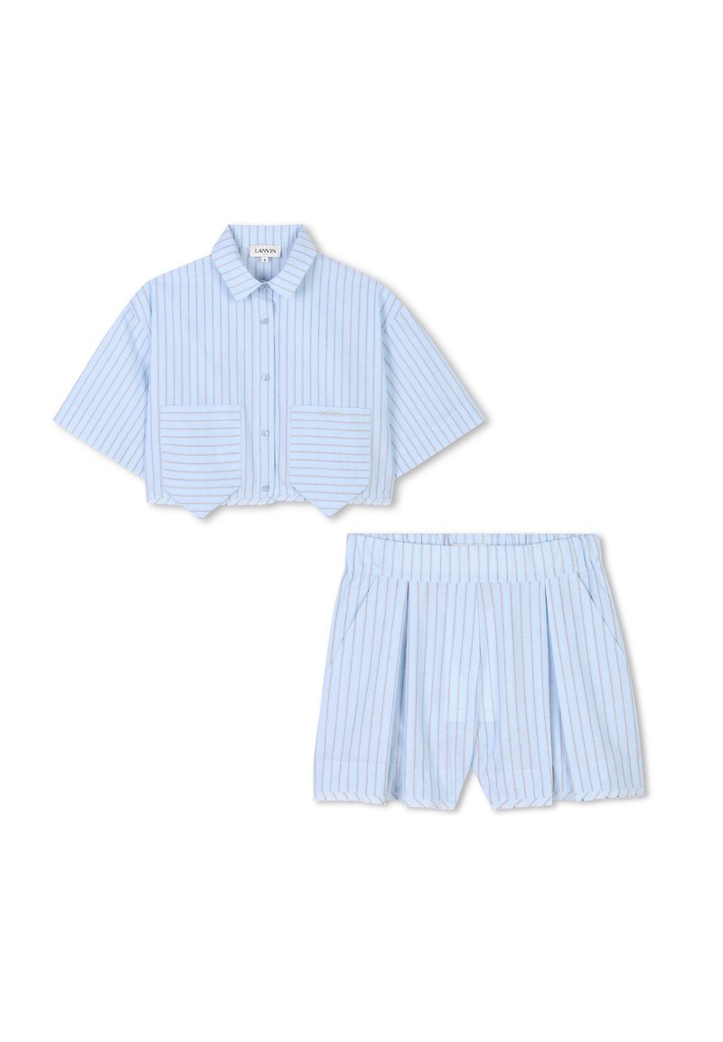 Chemise crop à rayures bleu clair avec un col et deux poches frontales, assortie avec un short plissé. Tissu en coton, coupe décontractée.