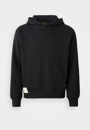 Melnā kapucīna mētelis, izgatavots no kokvilnas maisījuma. Iespējo kangaroo kabatu, ribotas piedurknes un mazu auduma etiķeti apakšējā sānā.