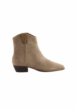Beige ruskinds ankelstøvle med spids tå, lav hæl i stabel og en trækflig. Glat tekstur med synlige syninger langs sålen.