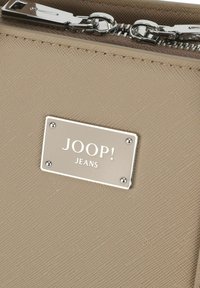 Bežna torbica s teksturirano tkanino, srebrnim priborom in kovinsko oznako blagovne znamke z napisom "JOOP! JEANS." Zadrga na zapiranju.