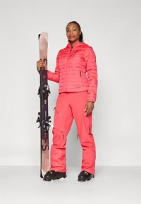 Heleroosa suusajope horisontaalsete joontega, sobivad roosad suusapüksid, mustad suusasaapad ja lumelaua koos mustade kinnitustega.