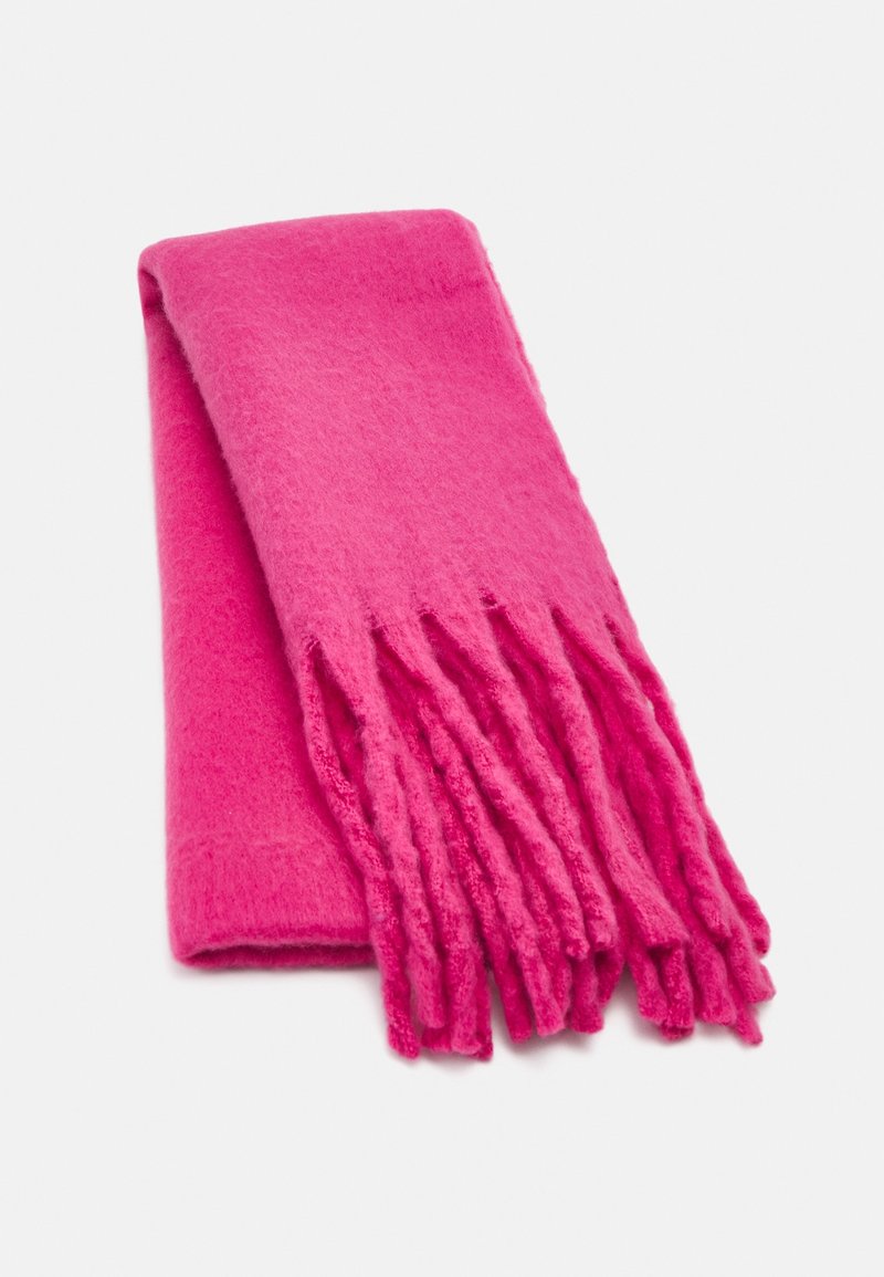 Écharpe douce rose vif pliée, avec de longues et épaisses franges à une extrémité, sur un fond blanc uni.
