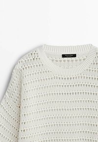 Pull blanc en tricot avec motifs ajourés horizontaux et col rond côtelé, montrant le haut devant et une partie de la manche.
