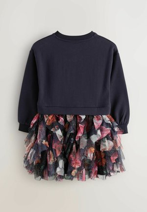Dunkelblauer Sweatshirt mit langen Ärmeln, kombiniert mit einem lebhaften, geschichteten Tüllrock, der florale Muster und Glitzer umfasst.
