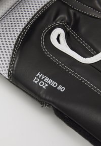 Crne kožne bokserske rukavice s mrežastim detaljima, bijelim šavovima i natpisom "HYBRID 80 12 OZ." Istaknuto zatvaranje na čičak oko zapešća.