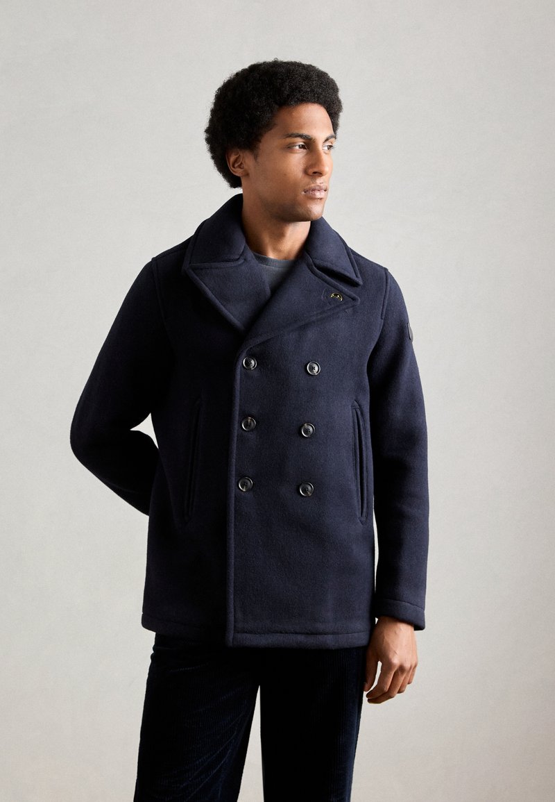 Marineblauer, doppelt genommerter Peacoat aus Wollmischung mit großen Revers, Knopfdetails und zwei seitlichen Taschen. Glatte Textur, taillierter Schnitt.