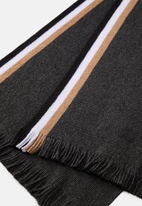 Cachecol em cinza escuro com riscas verticais em branco e castanho. Apresenta franjas ao longo das bordas. Textura suave e trançada.