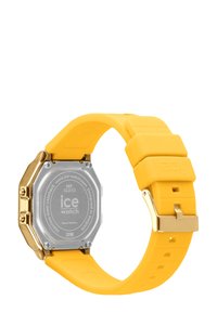 Montre avec un bracelet en silicone jaune et un boîtier octagonal en acier inoxydable doré. Présente un fond de boîte argenté avec le logo "ice watch". Étanche jusqu'à 30 mètres.
