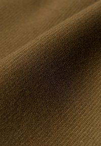 Close-up van bruin stof met een zachte, gestructureerde oppervlakte en subtiel diagonaal weefselpatroon.