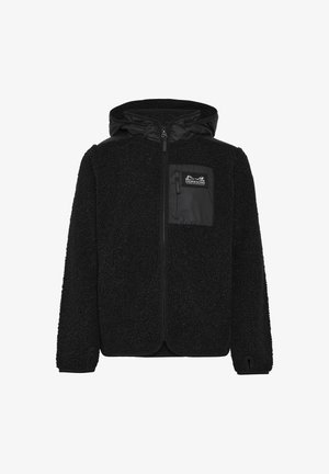 Blondes Kind im Stehen, trägt eine schwarze Fleecejacke mit Kapuze, schwarze wasserfeste Hose und schwarze Stiefel auf einem weißen Hintergrund.