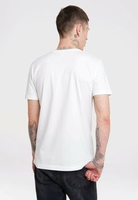 Weißes Baumwoll-T-Shirt mit kurzen Ärmeln, rundem Ausschnitt und glatter Textur, getragen mit dunkler Jeans. Minimalistisches Design, keine Grafiken.