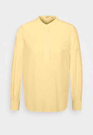 Herre langærmet gul henley skjorte med knaplukning og rund krave på en hvid baggrund.