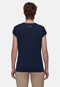 Granatowy t-shirt z podwiniętymi krótkimi rękawami, wykonany z miękkiego materiału. Posiada małe logo "MAMMUT" nad dekoltem. Gładka tekstura.