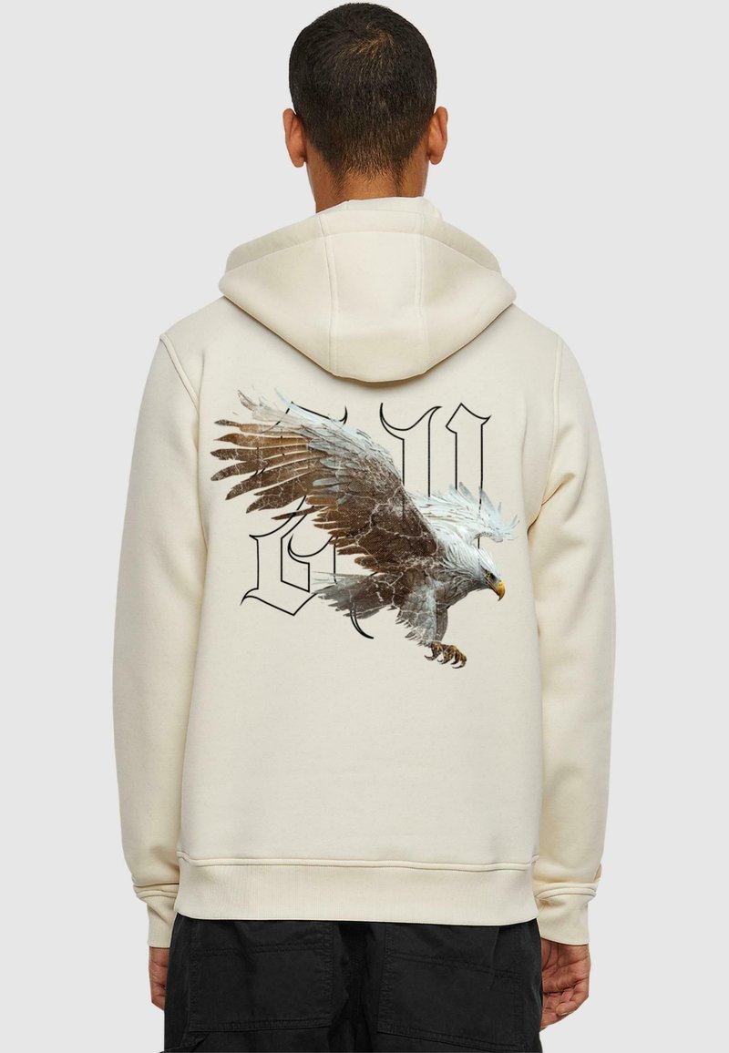 Cremfarbener Hoodie mit einem großen Adlerdesign und stilisierten Buchstaben auf dem Rücken. Weicher Stoff, lockere Passform und verstellbare Kapuze.